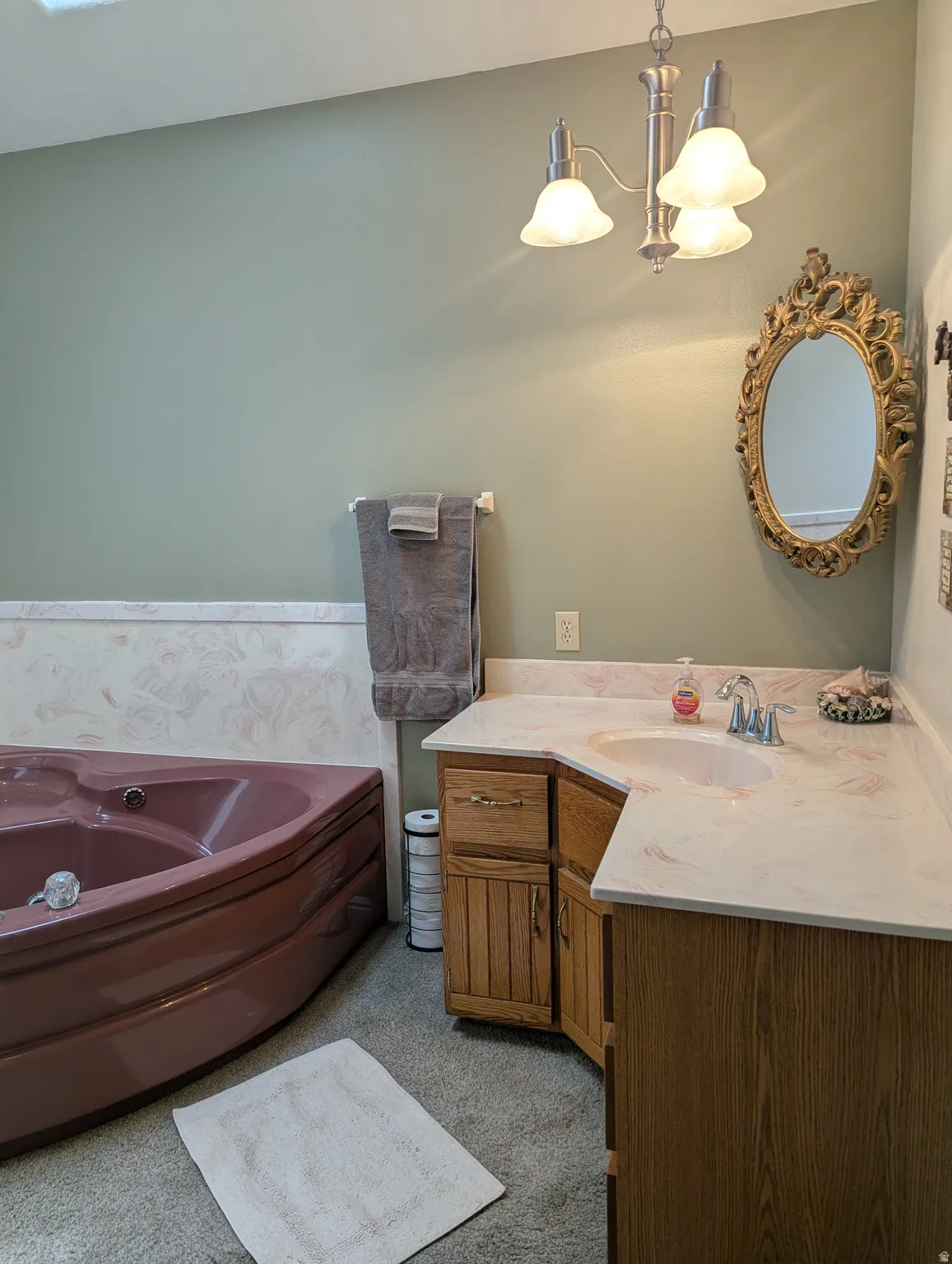 Corner soaking tub, dual-tone vanity with integrated sink, stone-finish countertop, and brushed nickel light fixture