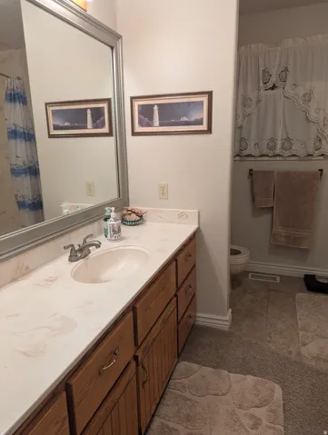 Single vanity with an integrated sink, patterned countertop, and wood-finish cabinetry