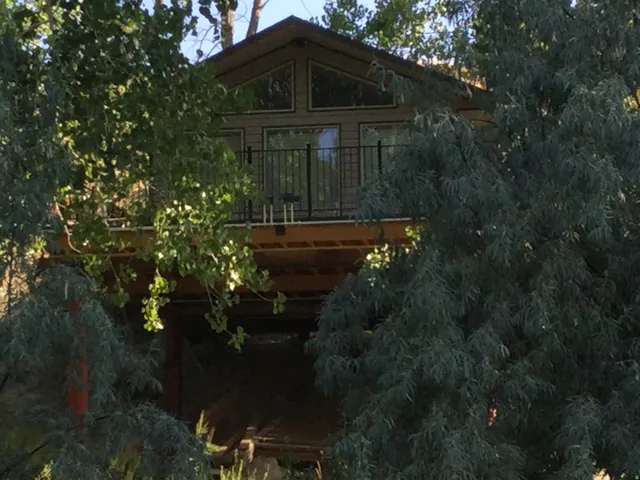 Exterior featuring a peaked roof, upper-level balcony with metal railing, and horizontal siding