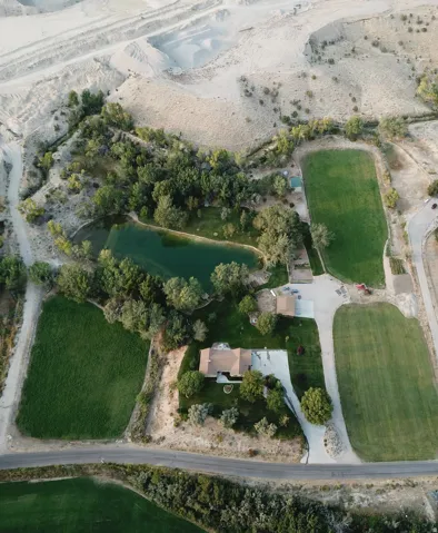 Expansive grounds featuring a private pond, mature trees, manicured lawns, and a private driveway