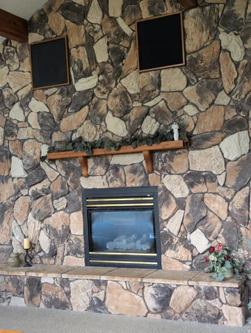 Floor-to-ceiling stone fireplace featuring a built-in firebox, stone hearth, and a wood mantel