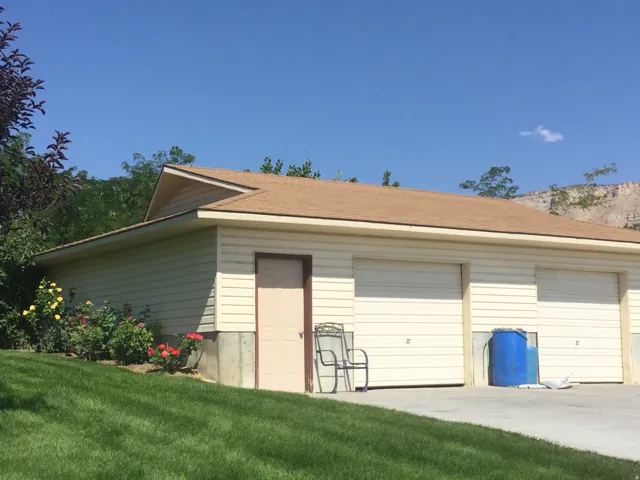 Garage structure with horizontal siding, two overhead garage doors, and a side entry door