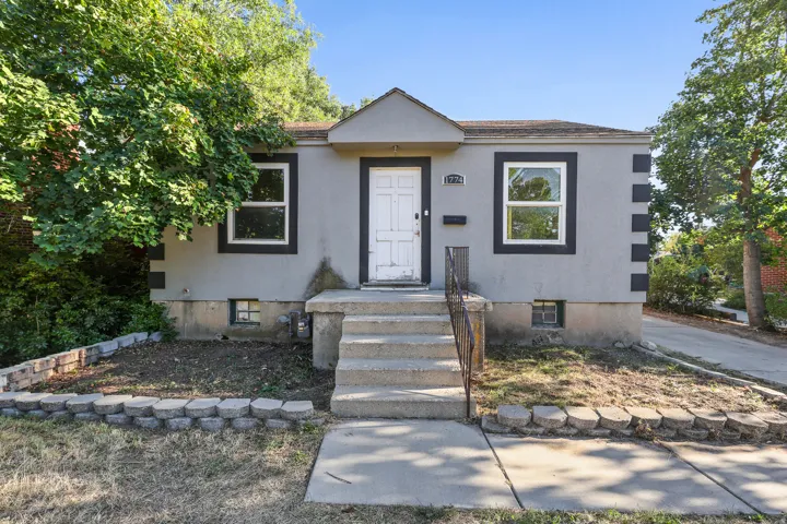Stucco exterior with contrasting trim, concrete front steps, and a wrought iron railing