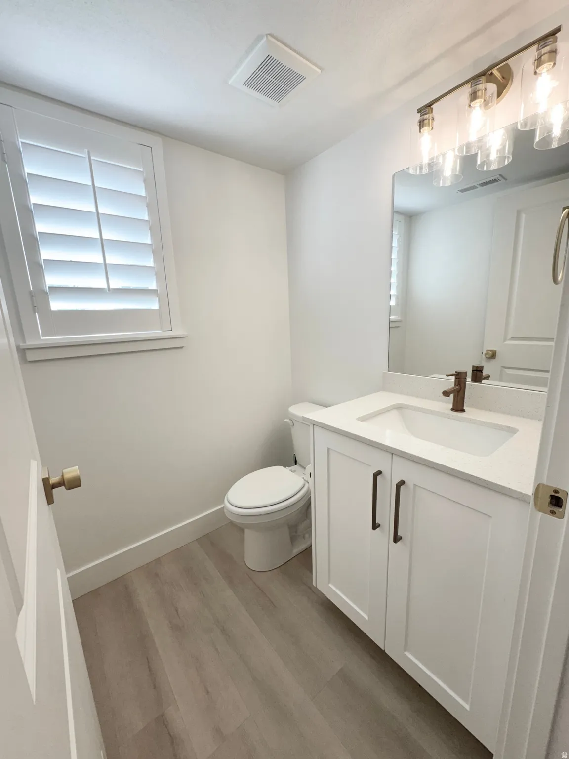 White shaker vanity with a single basin sink and bronze faucet