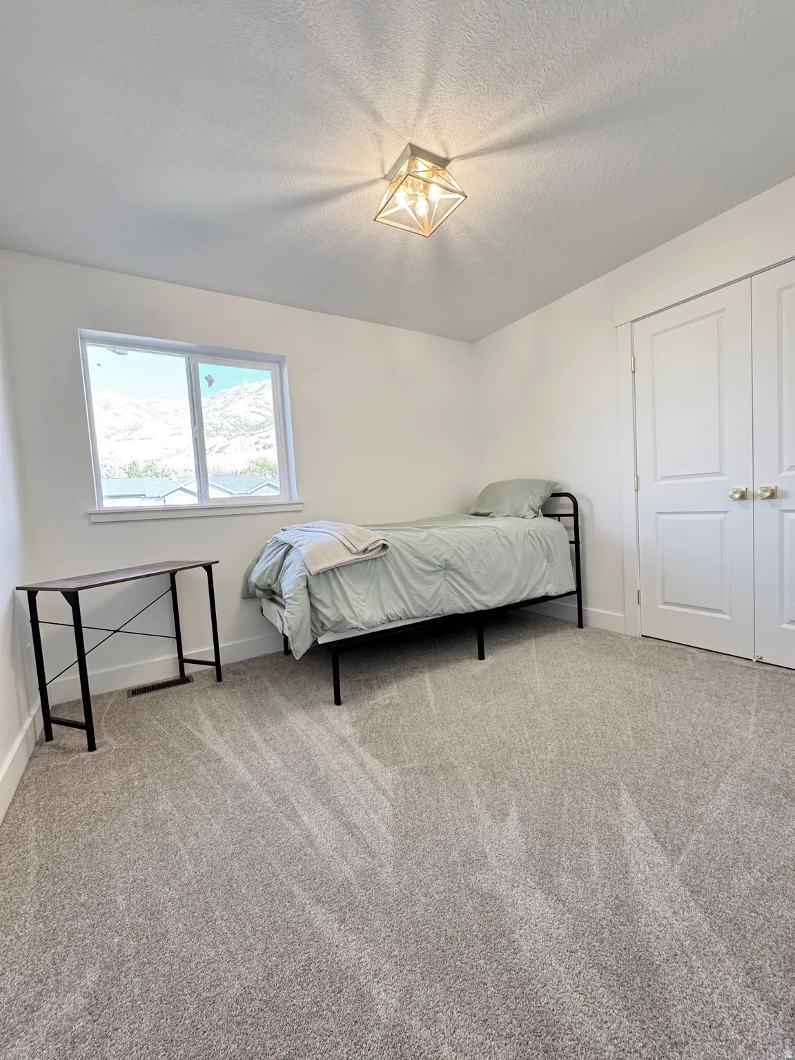 Neutral wall colors with carpeted flooring, featuring a window and a closet with bifold doors