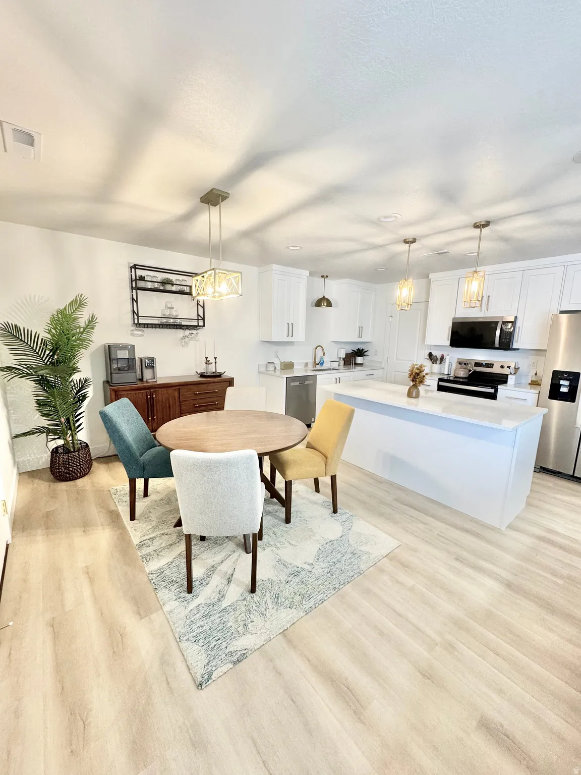 White cabinetry, stainless steel appliances, wood-finish flooring, recessed lighting, and kitchen island with countertop