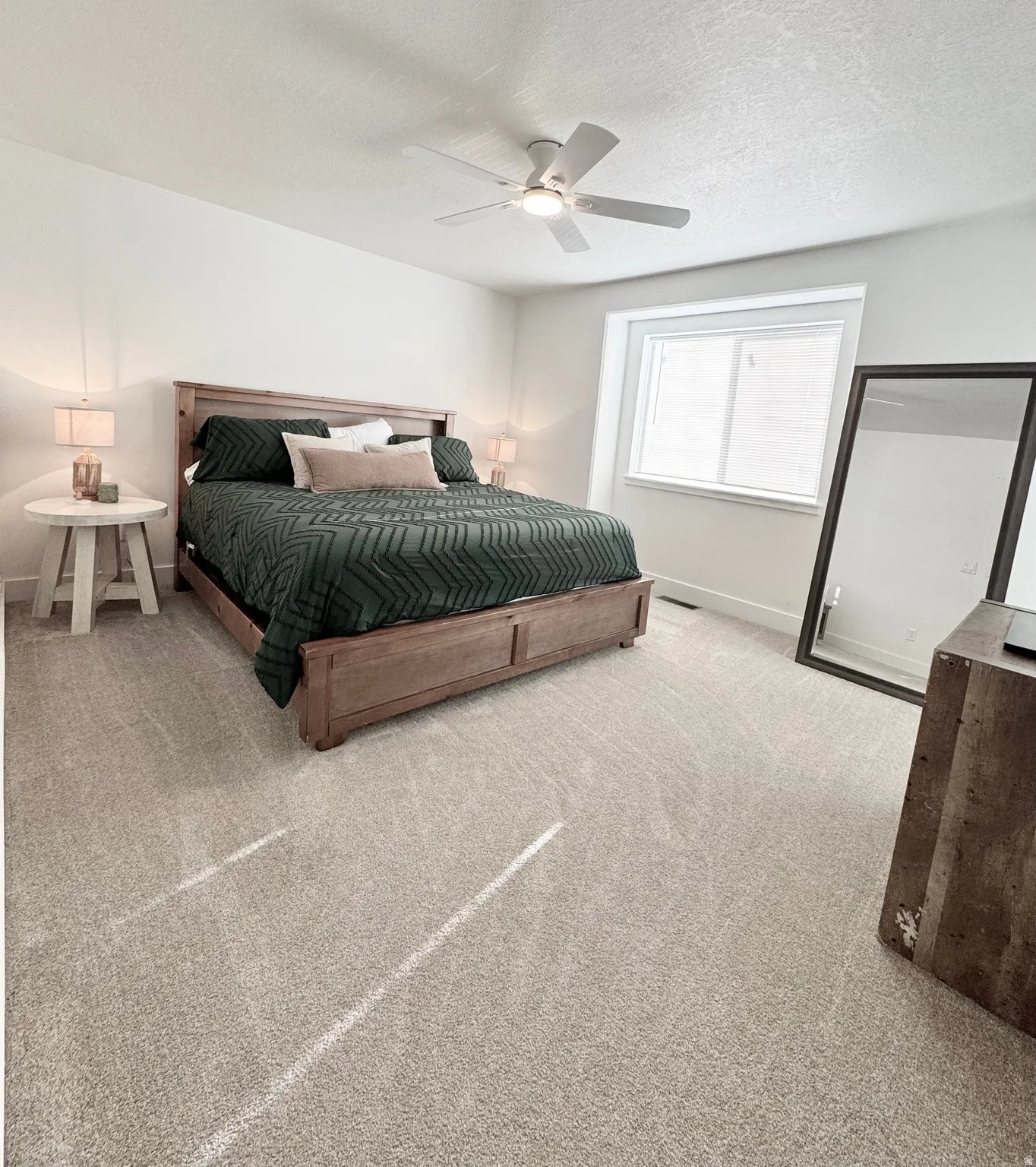 Broadloom carpeting, white walls, overhead ceiling fan with lighting, and a large window