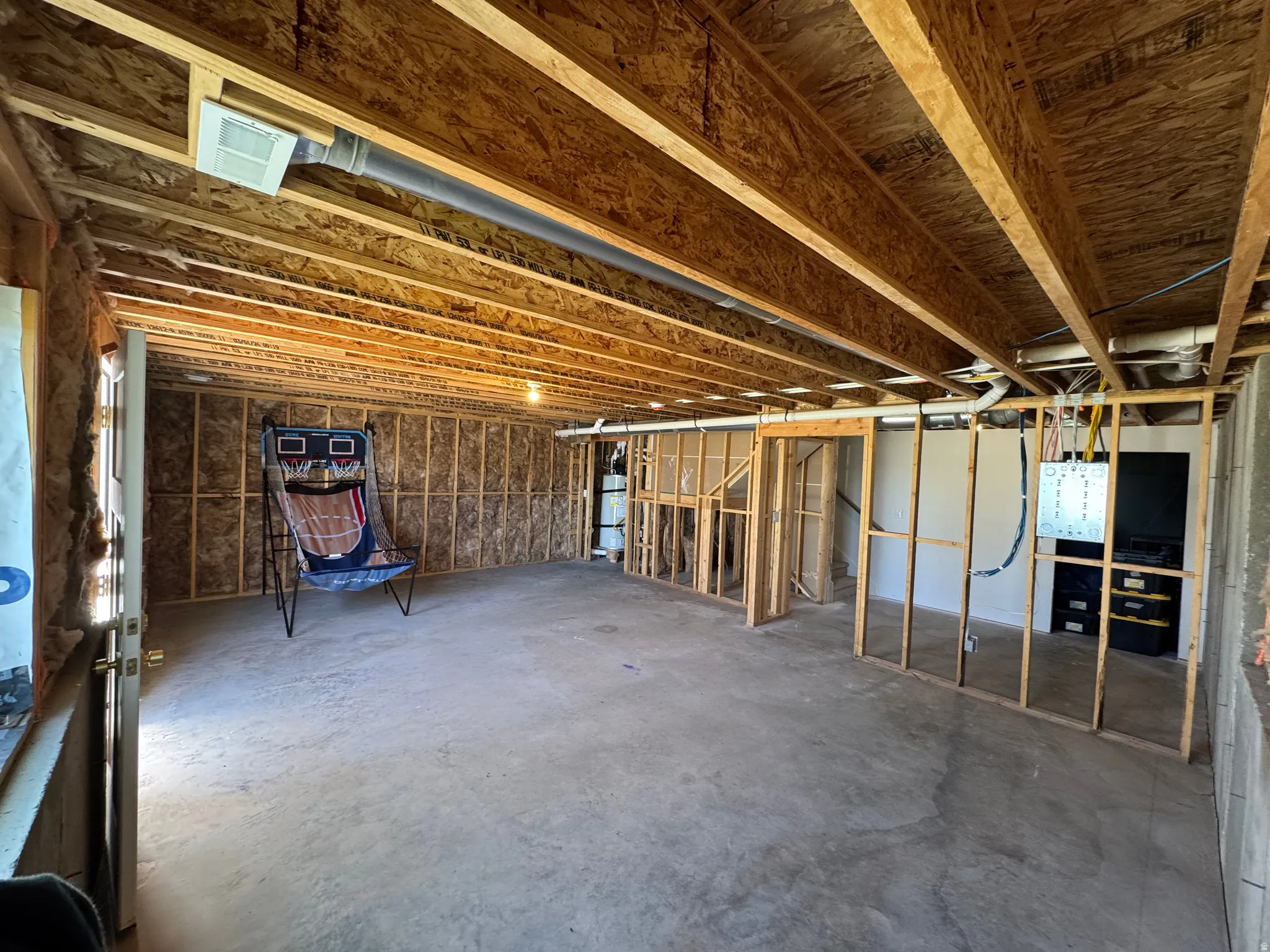Unfinished basement with exposed ceiling joists, concrete flooring, and framed walls
