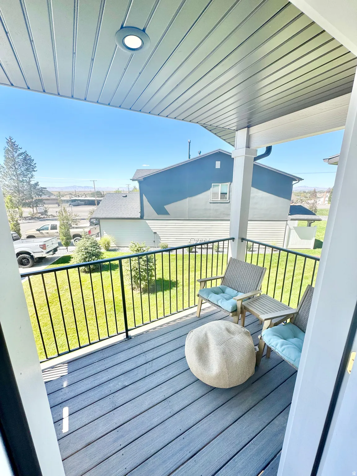 Balcony with composite decking, black metal railing, and recessed overhead lighting