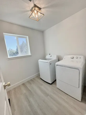 Laundry area featuring wood-finish flooring, a contemporary ceiling light fixture, and a window
