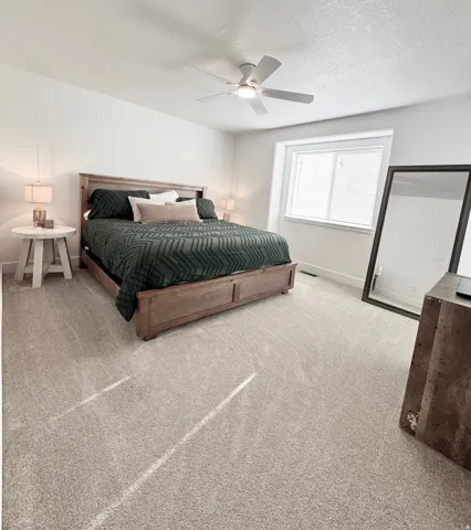 Broadloom carpeting, white walls, overhead ceiling fan with lighting, and a large window