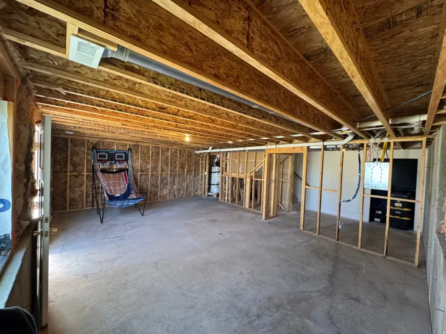 Unfinished basement with exposed ceiling joists, concrete flooring, and framed walls