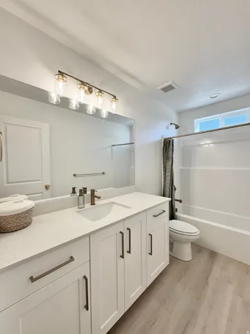 Double vanity with white cabinetry, bronze hardware, and light-colored countertops