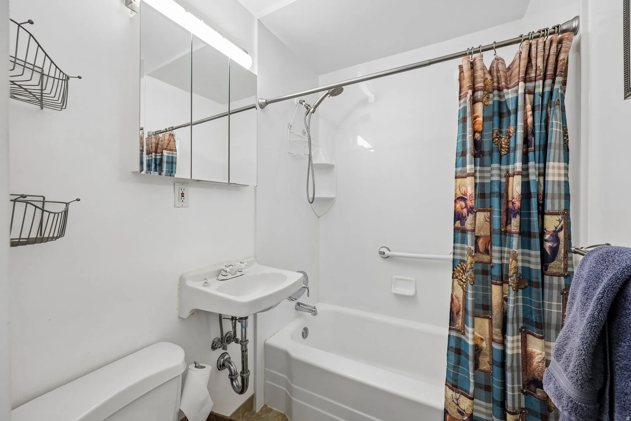 White ceramic wall-mounted sink, medicine cabinet with mirrored doors, built-in bathtub with white surround, grab bar, and wall-mounted showerhead