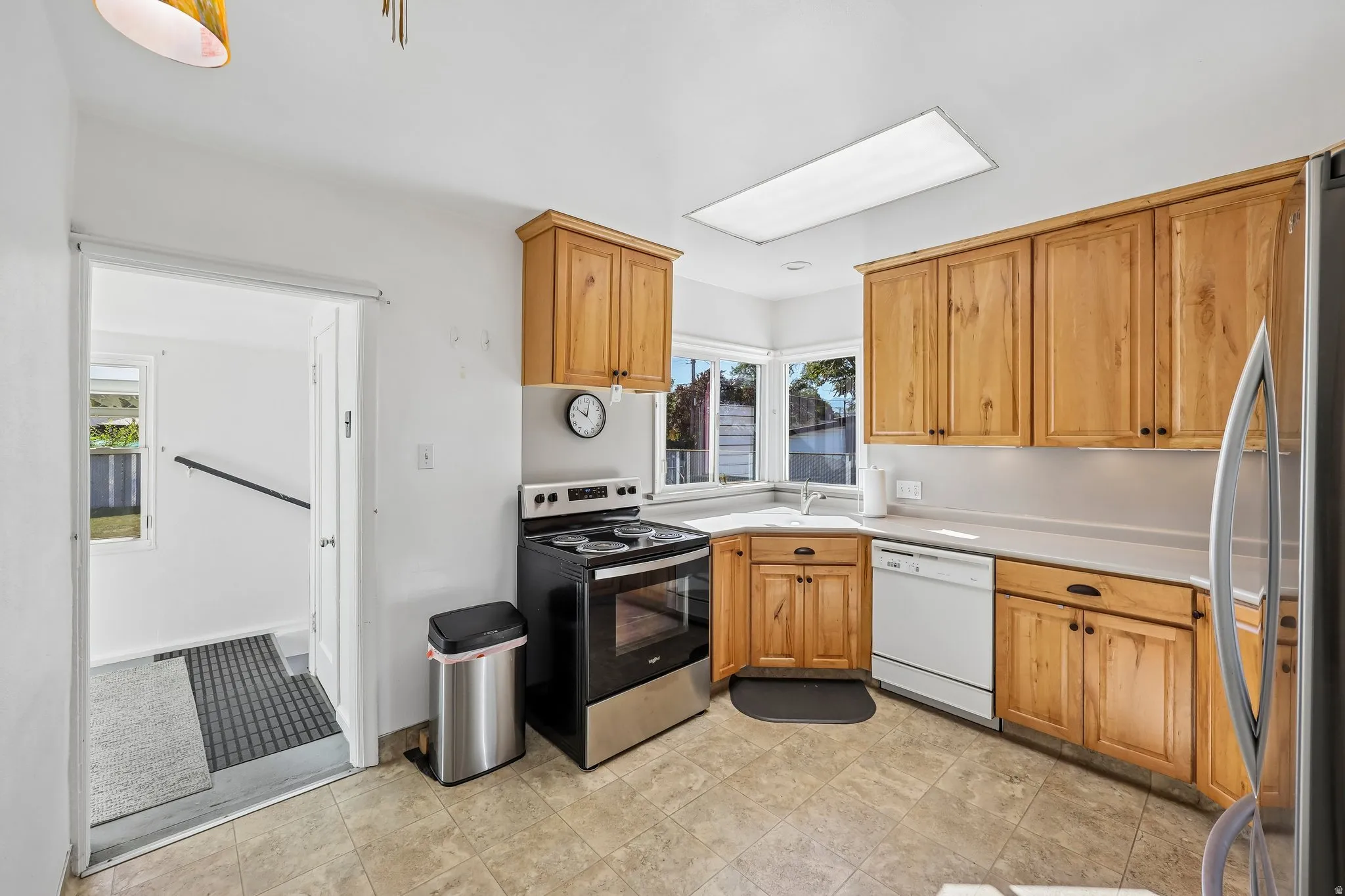 Kitchen featuring wood cabinetry, an integrated sink, a built-in dishwasher, and a skylight