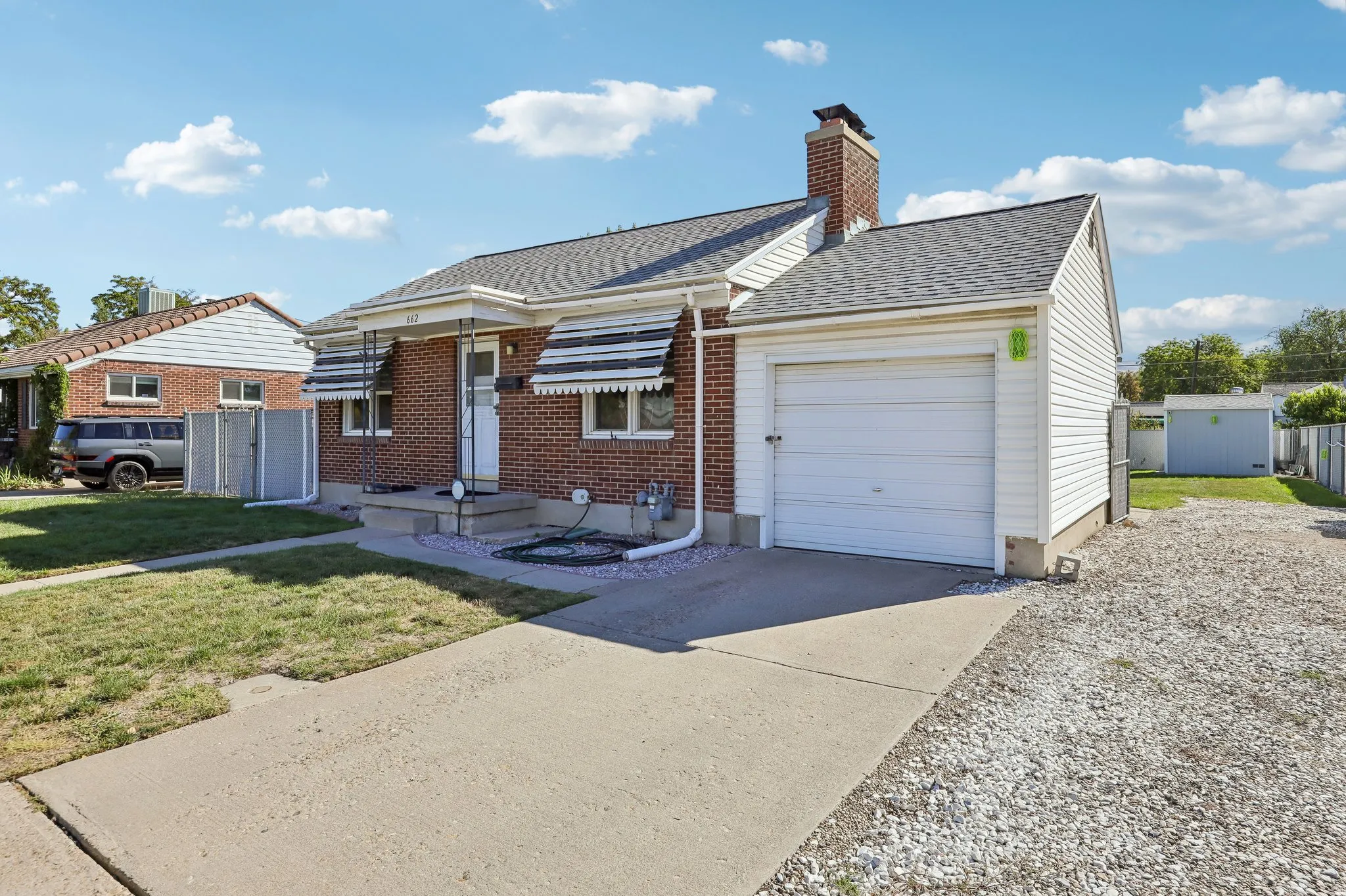 Brick exterior with a peaked roof, attached garage, and paved driveway