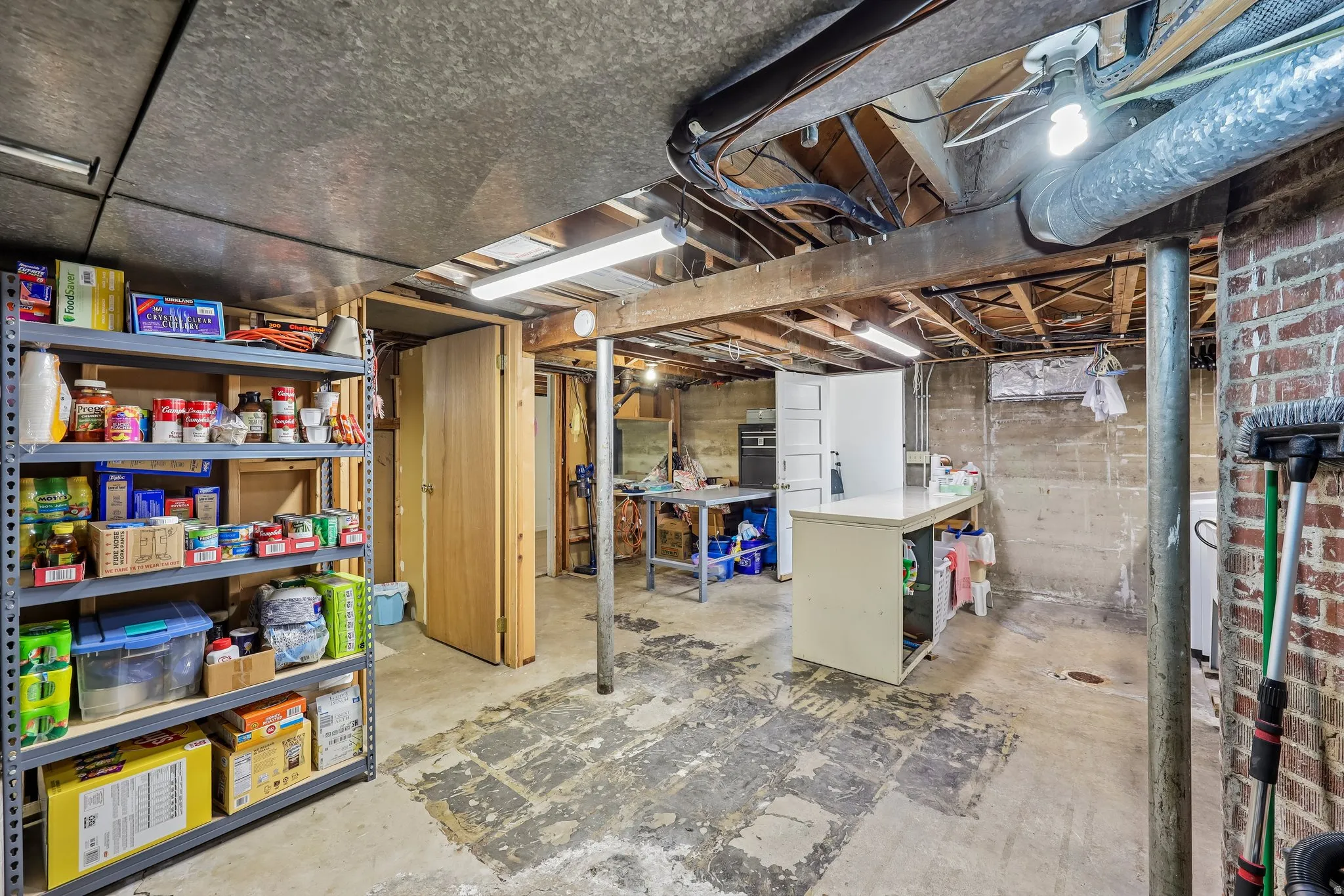 Unfinished basement featuring exposed brick, concrete walls, and concrete flooring