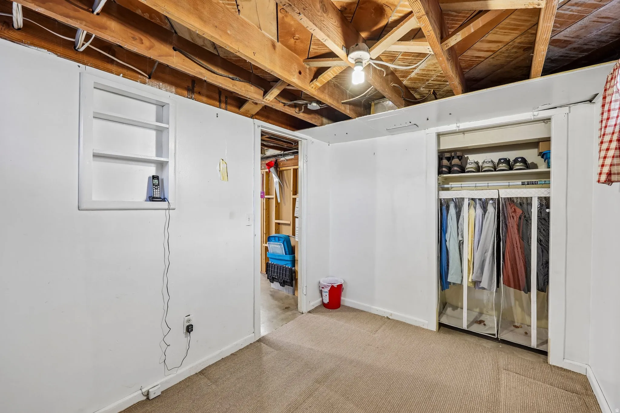 Exposed wood ceiling beams, white painted walls, and carpet flooring