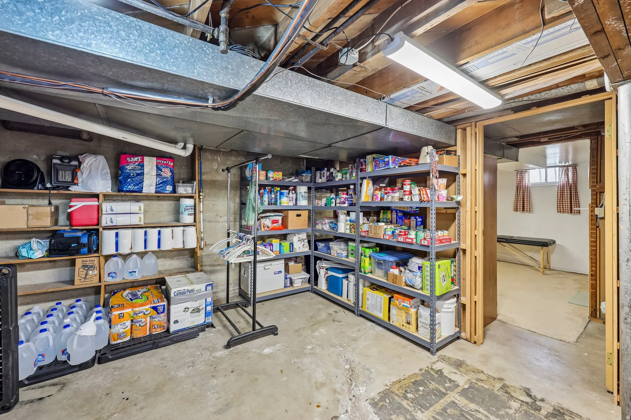 Unfinished basement with exposed ceiling joists, concrete flooring, and built-in shelving