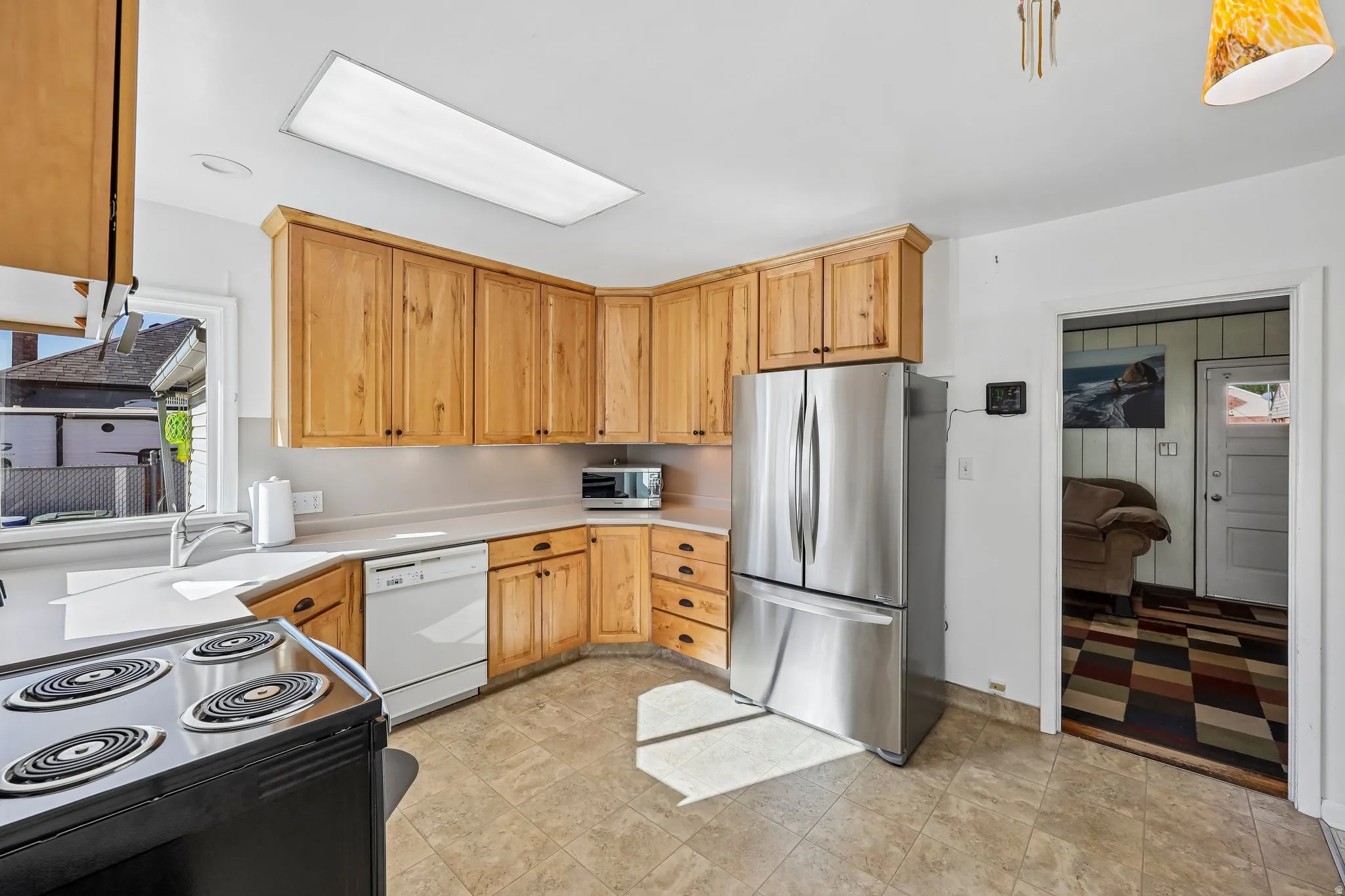 Kitchen featuring wood cabinetry, light-toned countertops, a stainless steel refrigerator, and tiled flooring