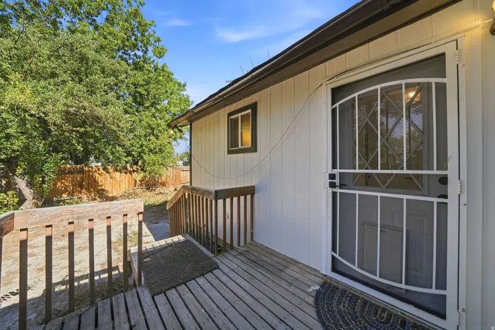 Hardwood deck with railings, exterior siding, security screen door, and a privacy fence