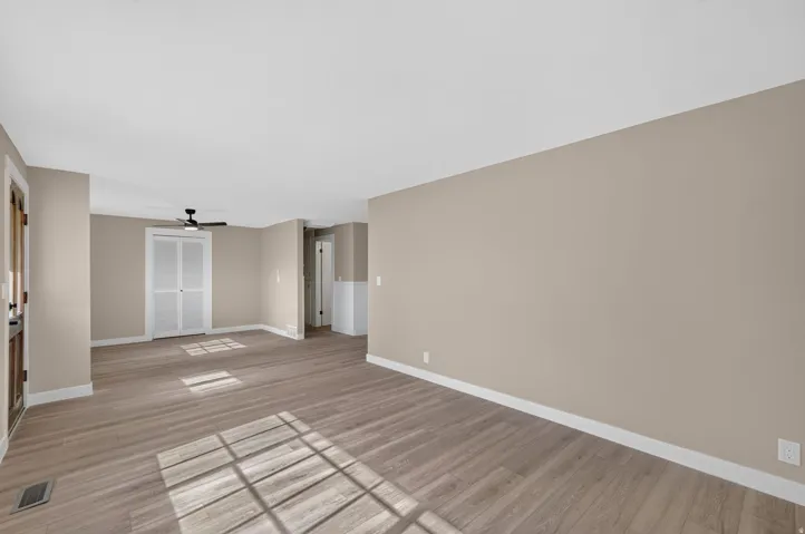 Spacious room with wood-finish flooring, neutral-toned walls, and white trim