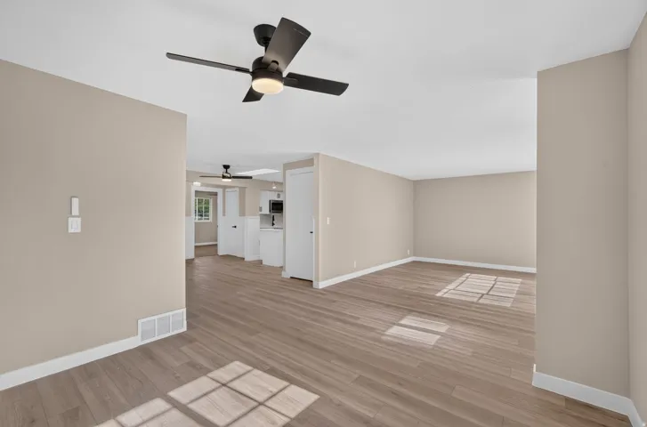 Expansive open-concept living space with wood-finish flooring, neutral wall tones, and recessed lighting