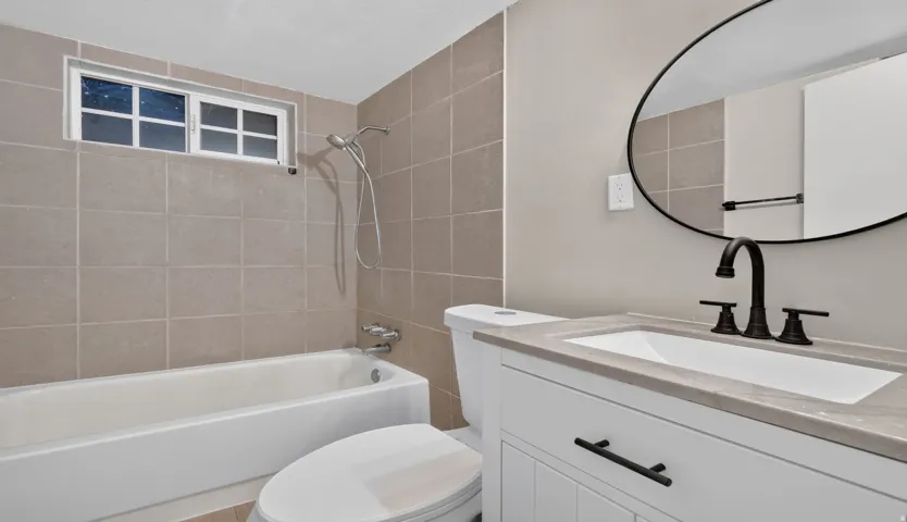 White vanity with dark hardware, rectangular sink, and stone-finish countertop