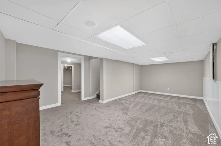 Spacious room with plush gray carpeting, neutral wall paint, and white wainscoting