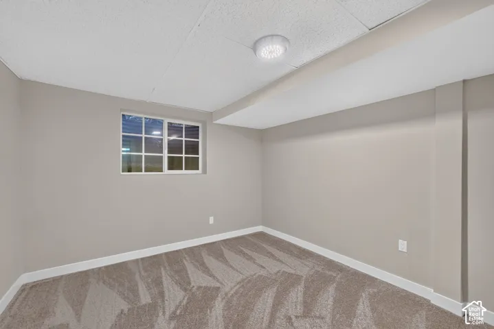 Window with white grid muntins, recessed ceiling light fixture, textured ceiling, light gray wall paint, and patterned carpet