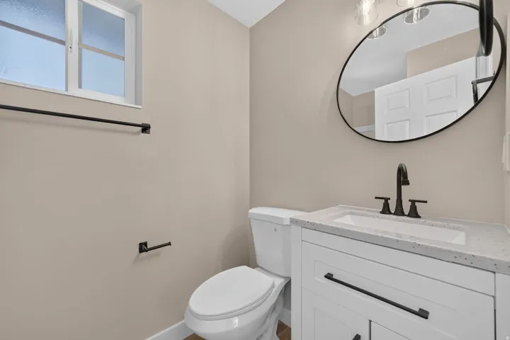 White vanity with black hardware, integrated sink, and speckled countertop