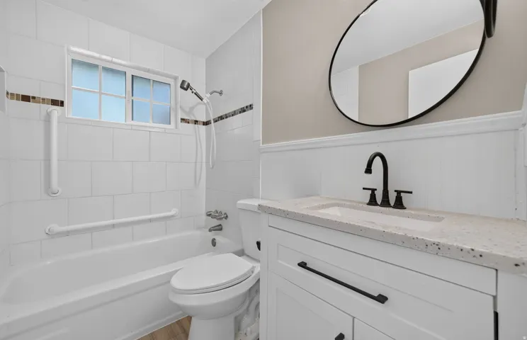 White tiled shower and tub combination with decorative accent tile
