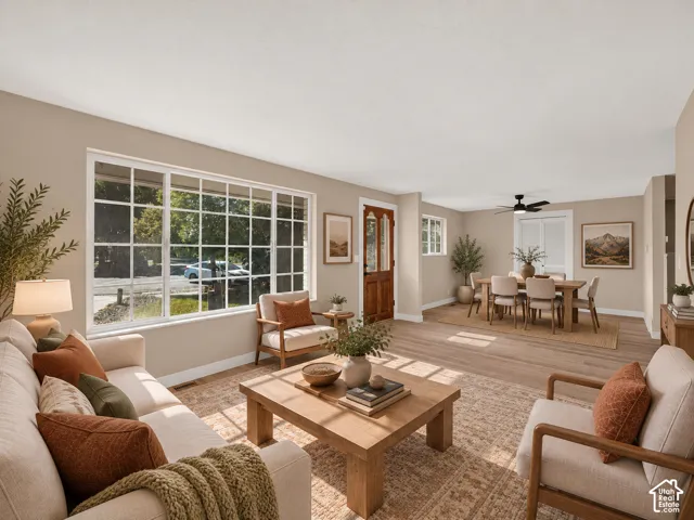 Expansive living area with wood-finish flooring, a large grid-pane window, and a paneled entry door