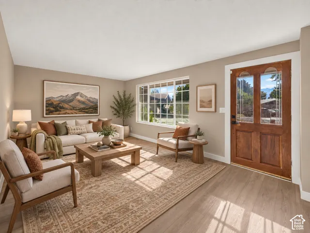 Wood-finish flooring throughout, framed window with grid pattern, solid wood entry door with decorative glass panels, neutral wall tones, and recessed lighting