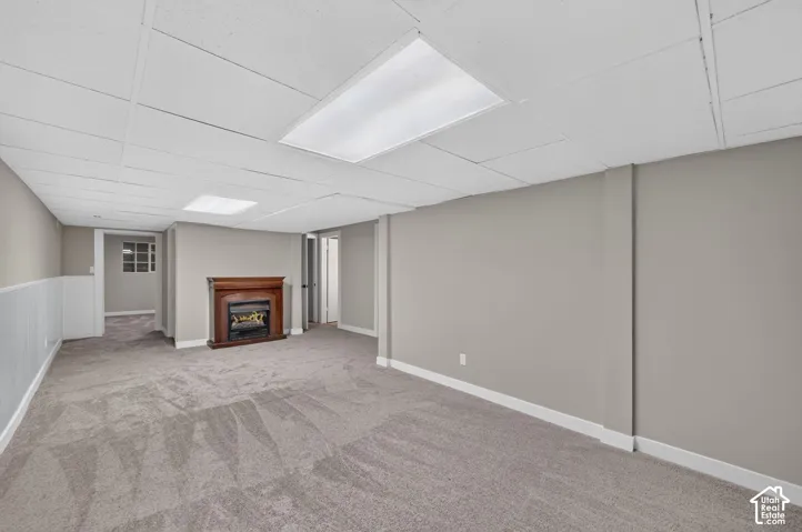 Spacious room featuring neutral carpeting, a wood-finish fireplace, and paneling accents