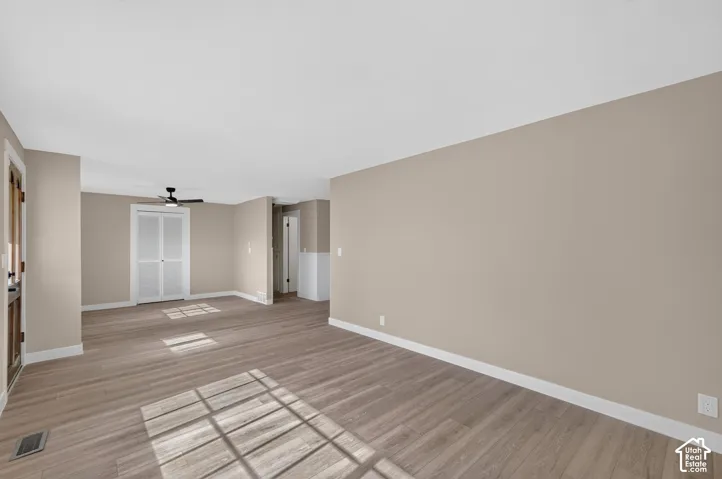 Spacious room with wood-finish flooring, neutral-toned walls, and white trim
