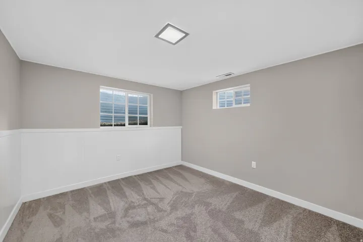 Neutral wall paint, white wainscoting, plush carpet, recessed ceiling light, and multiple windows