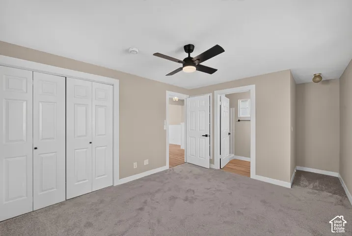 Ceiling fan with integrated lighting, neutral wall paint, white trim, paneled bifold closet doors, and carpet flooring