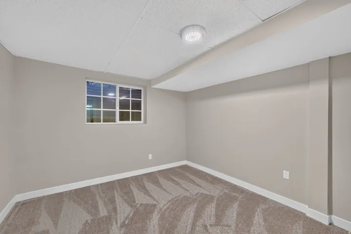 Window with white grid muntins, recessed ceiling light fixture, textured ceiling, light gray wall paint, and patterned carpet