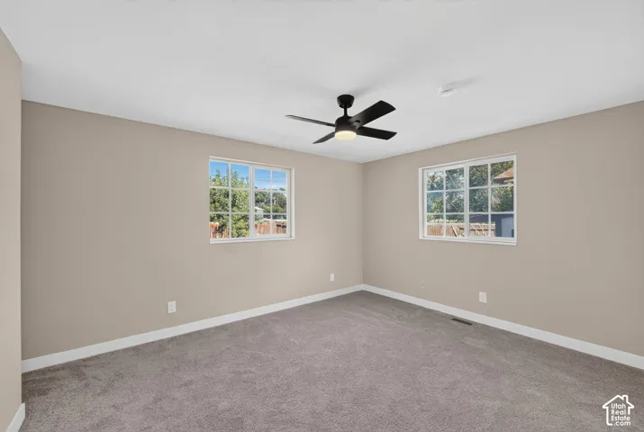 Carpeted flooring, neutral wall paint, two pane windows, and a ceiling fan with integrated lighting