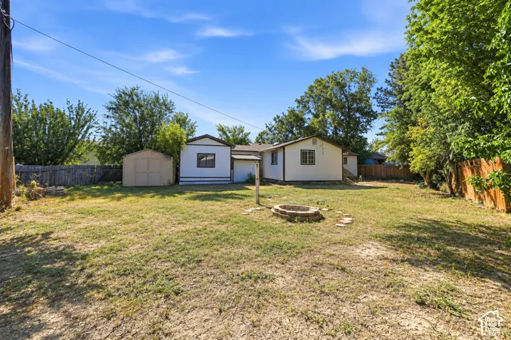 Expansive backyard featuring a stone-lined fire pit, perimeter fencing, and mature trees