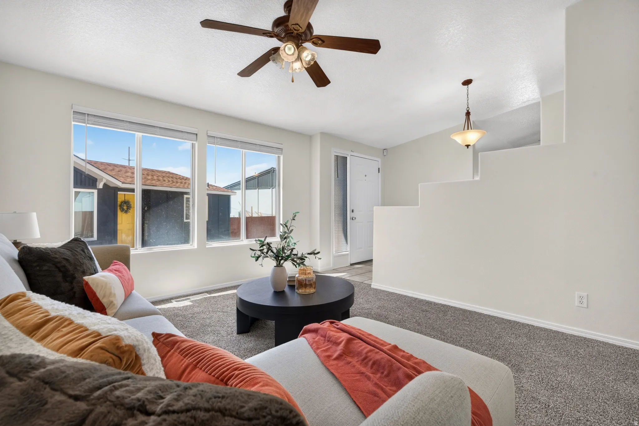 Neutral wall paint, ceiling fan with integrated lighting, recessed entry, pendant light fixture, and light gray carpet