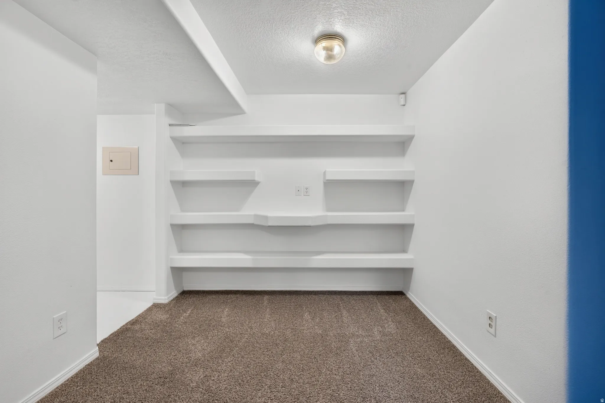 Built-in shelving, recessed ceiling light, wall-to-wall carpeting, and white painted walls