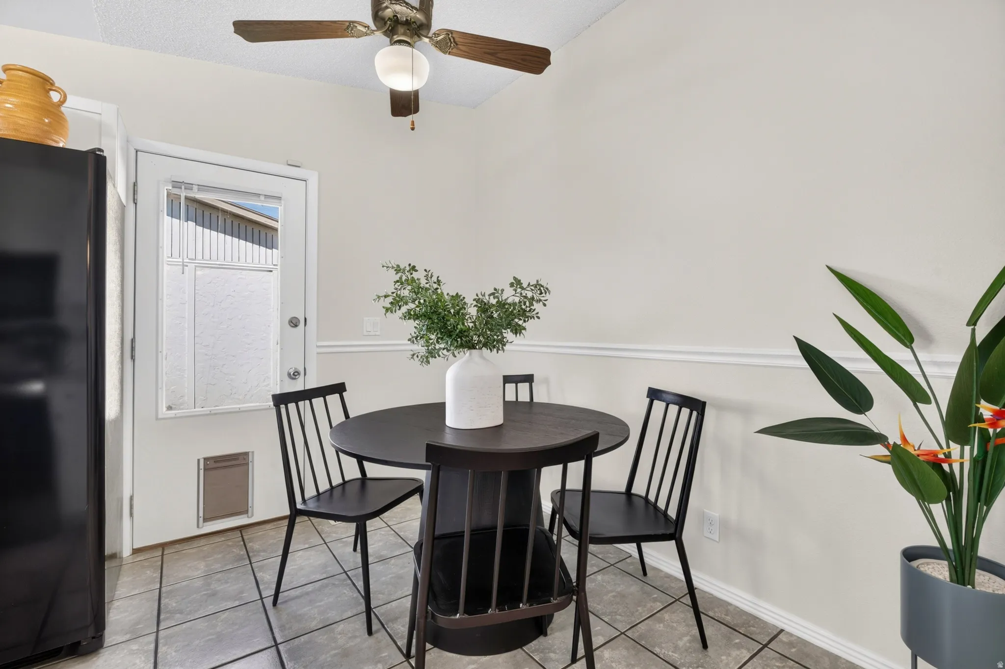 Kitchen area featuring a ceiling fan with light, tiled flooring, built-in refrigerator, glass-paned door, and lower wall molding