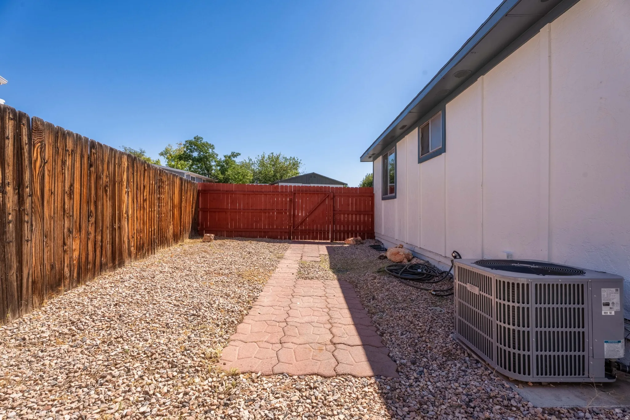 Private outdoor space featuring a red wood fence, a natural wood fence, and a paver pathway