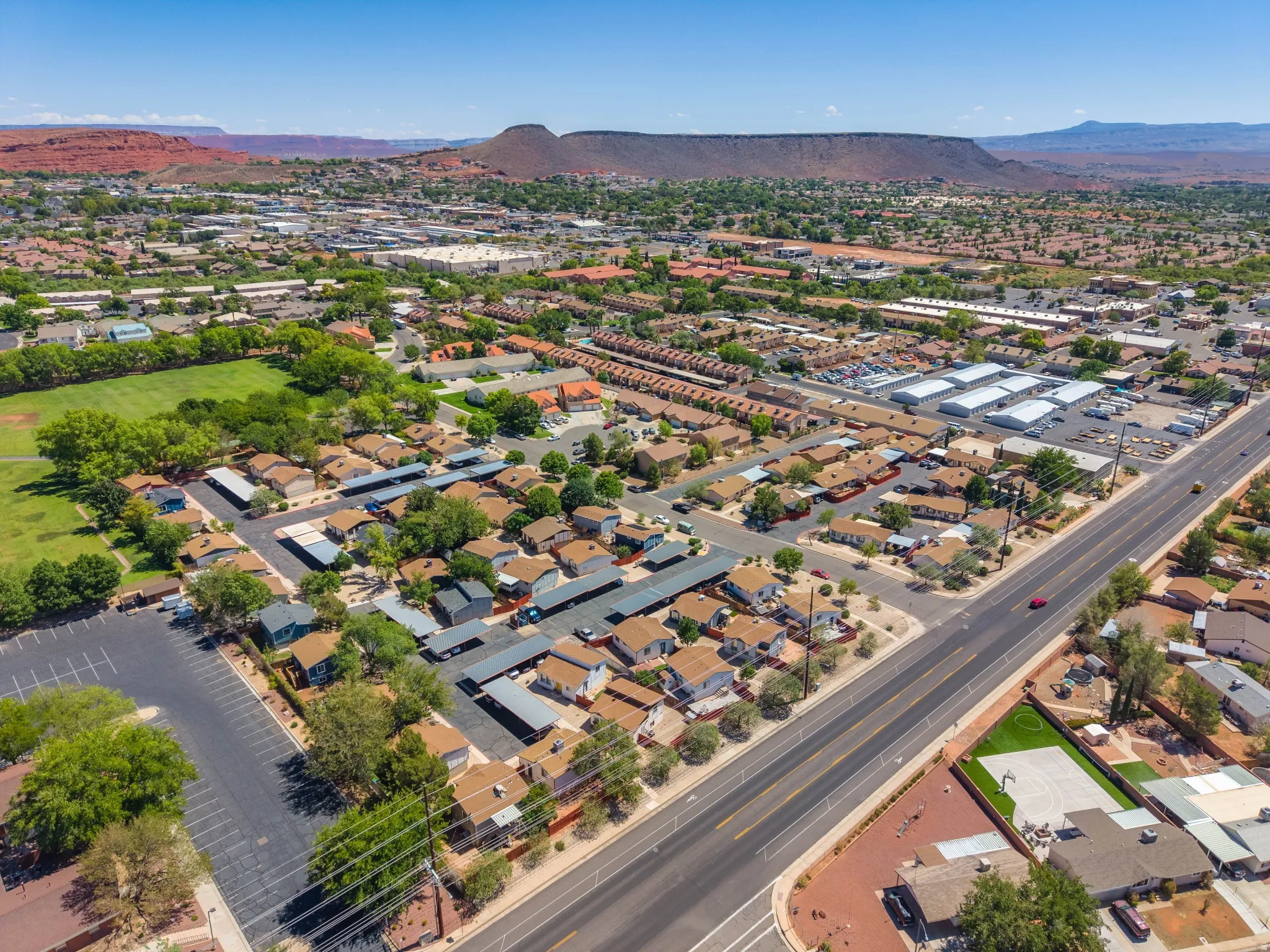 Aerial perspective of a developed residential and commercial area with prominent red rock formations in the background