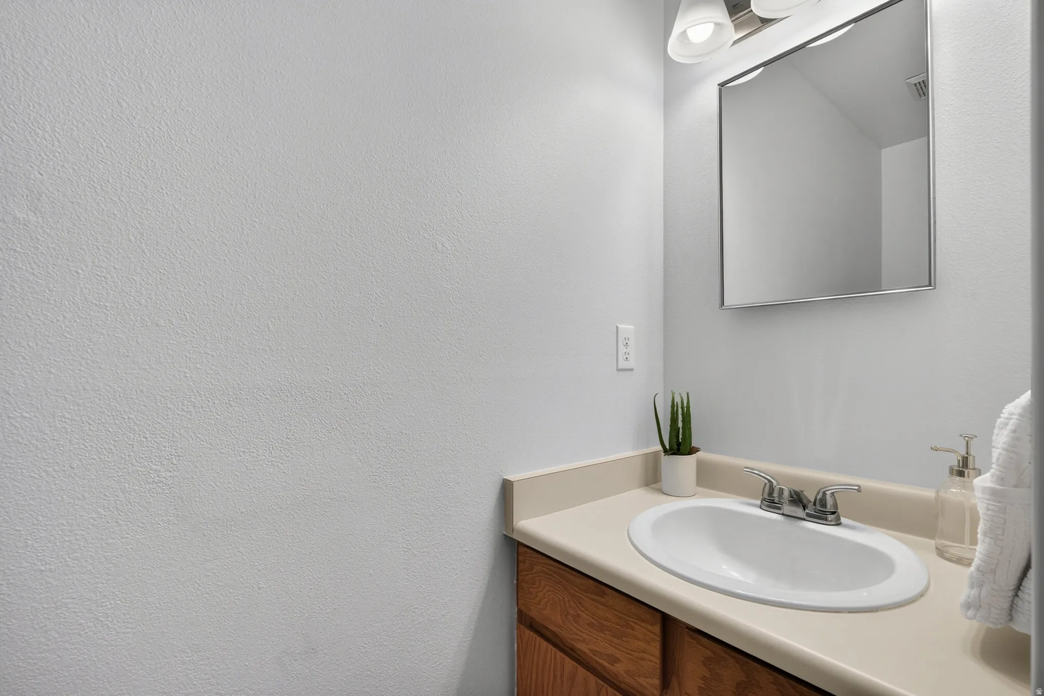 Bathroom vanity featuring a light-toned countertop, undermount sink, and chrome faucet