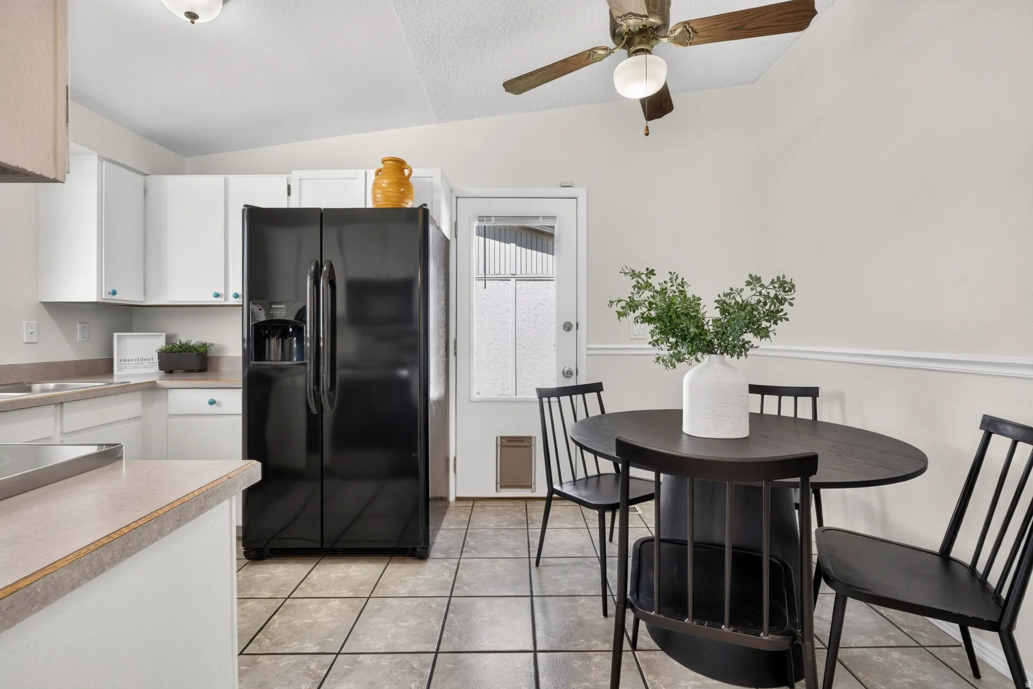 Kitchen featuring white cabinetry, a black side-by-side refrigerator, tile flooring, and a ceiling fan