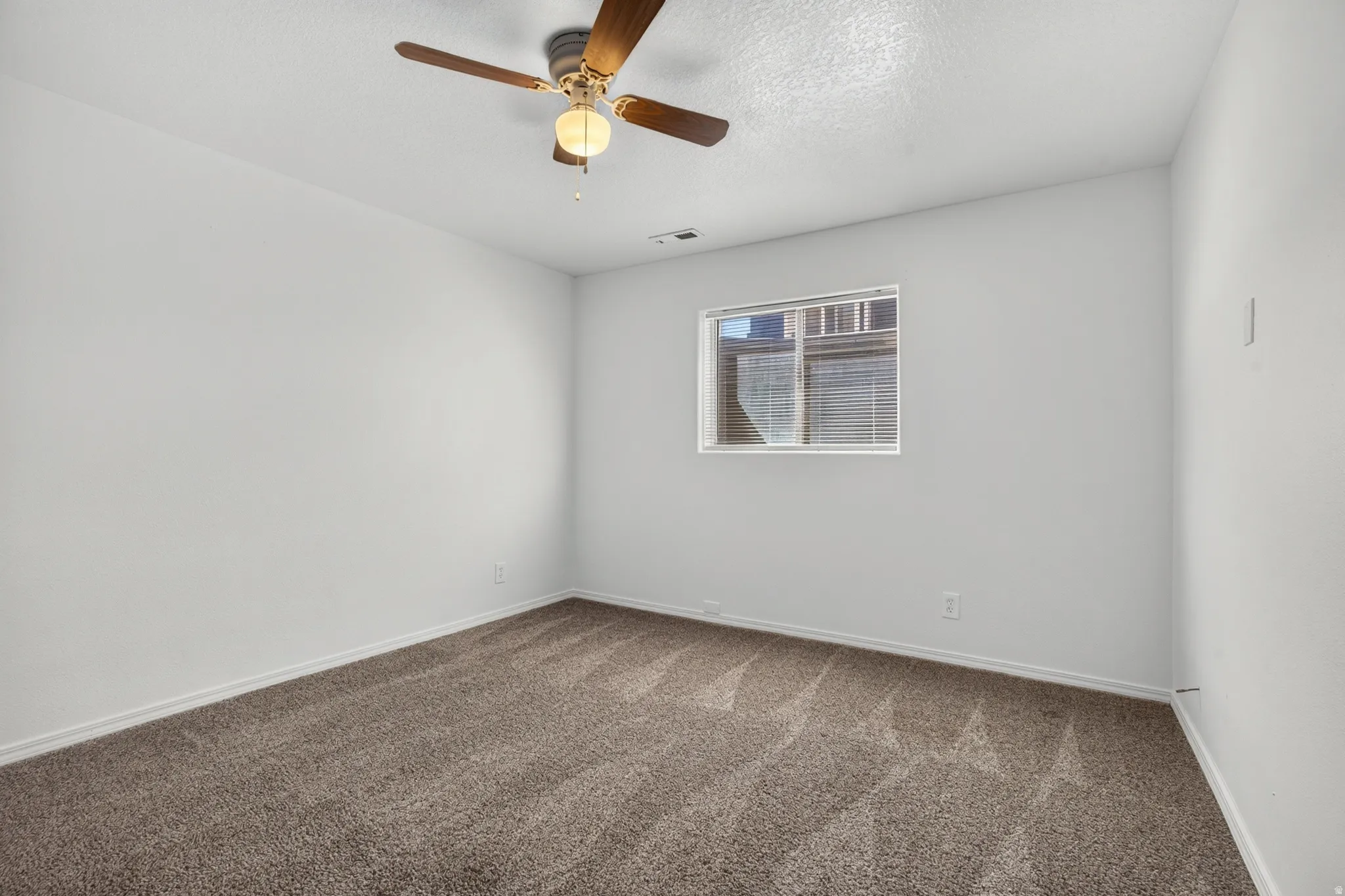 Neutral wall paint, window with blinds, ceiling fan with integrated lighting, and carpet flooring