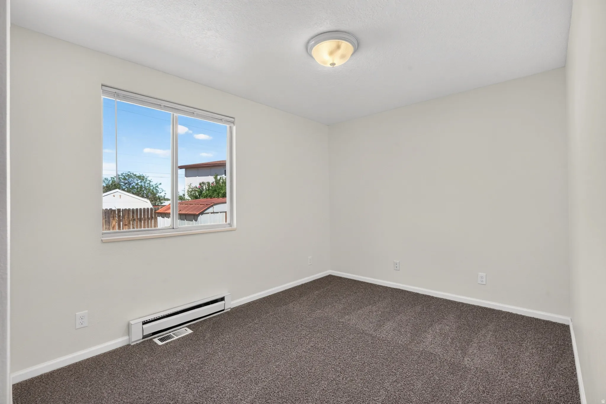 Neutral wall color, wall-to-wall carpeting, and flush mount ceiling light